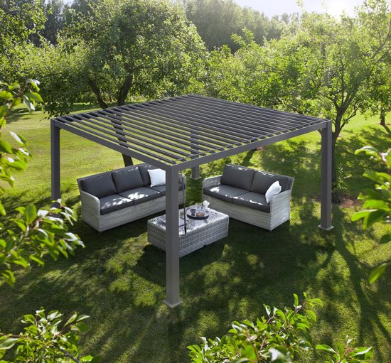 Eine Pergola mit Lamellendach steht auf einer Rasenfläche zwischen Bäumen und bietet mit zwei gepolsterten Sofas und einem Couchtisch einen gemütlichen Außenbereich. Sonnenlicht fällt durch die Blätter und die verstellbaren Dachlamellen.